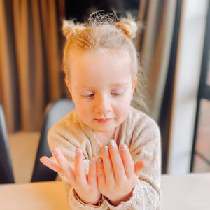 little girl with nail polish and nail stickers on her fingers