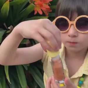 Little girl wearing yellow putting on kids lip gloss by No Nasties Kids